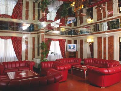 Elegant hotel lounge with red leather sofas, mirrored ceilings, and warm lighting.