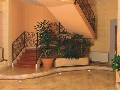 Elegant hotel staircase with wrought iron railing and plants in the entrance area.