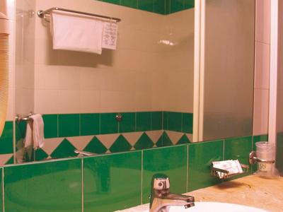 Bright bathroom with green and white tiles, sink, and hanging towel.