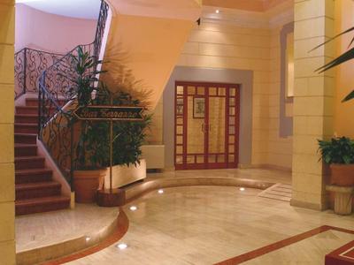 Bright hotel hallway with curved stairs and decorative railings.