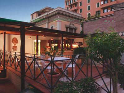 A quiet terrace with tables and chairs in front of a multi-story building at dusk.