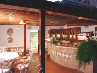 Cozy hotel bar with bar stools, plants, and warm evening lighting.