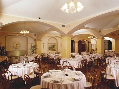 Elegant hotel restaurant with round tables, white tablecloths, and classic wooden chairs.