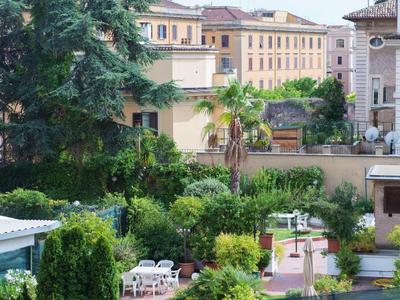 View of a garden with tables and chairs in front of buildings in sunny weather