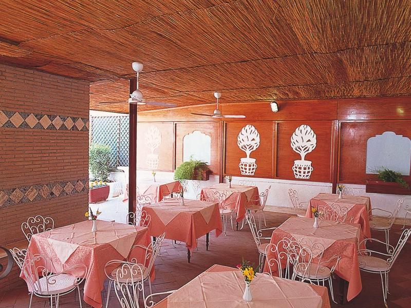 Covered hotel terrace area with several tables, chairs, and set tables.