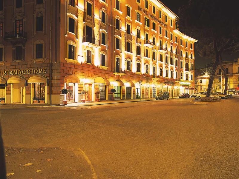Illuminated hotel building at night with multiple windows and curved street layout.