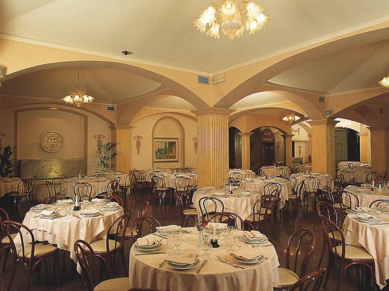Elegant traditional restaurant with round tablecloths and dark wooden chairs under high vaulted ceilings.
