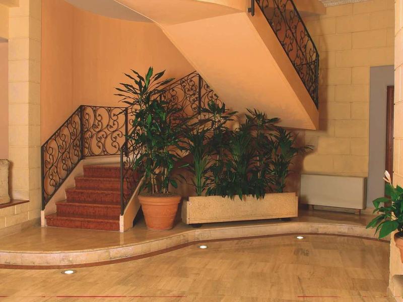 Elegant hotel staircase with wrought iron railing and plants in the entrance area.
