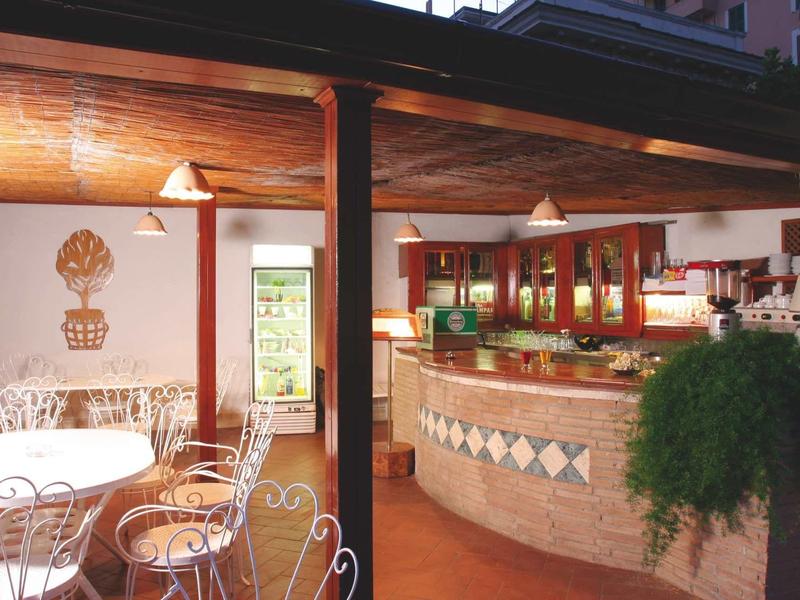 Cozy courtyard with tables and chairs next to a bar and plants.