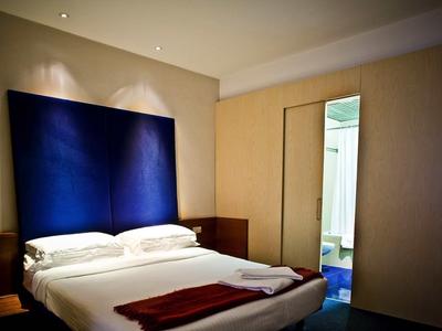 Modernes Schlafzimmer mit großem Bett, blauem Kopfteil und einem großen Spiegel an der Wand.