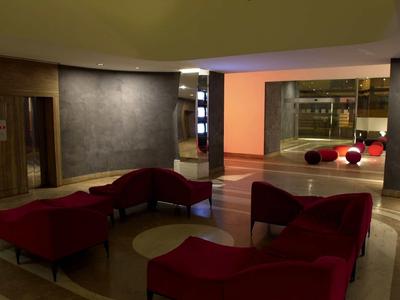 Innenraum mit roten Sitzmöbeln, grauen Wänden und indirekter Beleuchtung in warmen Farben.