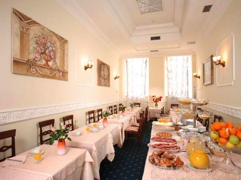 Elegantní snídaňová místnost s prostřenými stoly a bufetem s ovocem a studenými pokrmy.