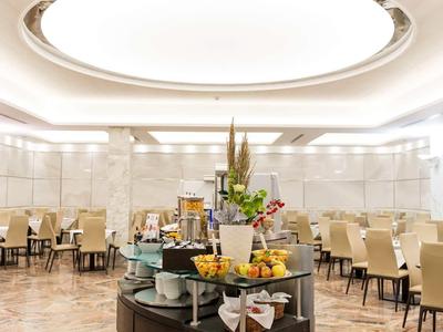 Ein heller, eleganter Speisesaal mit rundem Buffet und gedeckten Tischen auf Parkettboden.