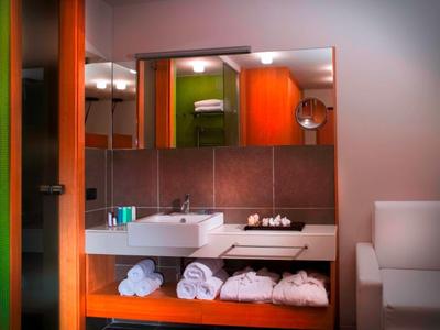 Moderne Badezimmer mit Waschbecken, Handtüchern und Holzregalen in warmem Licht.