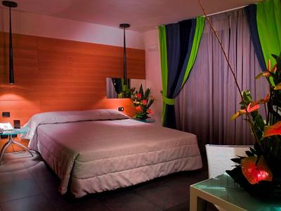 Gemütliches Schlafzimmer mit großem Bett, warmem Holz, grünen Vorhängen und Pflanzen.