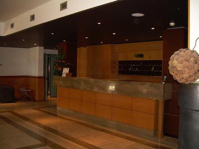 Hotelrezeption mit Holzverkleidung und Marmortheke in einem eleganten Empfangsbereich.