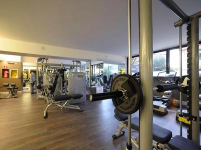 Moderner Fitnessraum mit verschiedenen Trainingsgeräten und großer Fensterfront