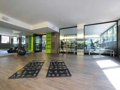 Moderner Fitnessraum mit großen Spiegeln, Yogamatten und Fitnessbällen.