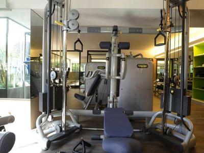 Fitnessraum mit Krafttrainingsgeräten und Bank auf dunklem Boden in modernem Hotel.