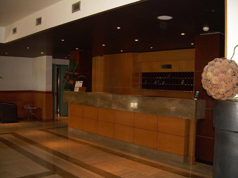 Rezeptionstresen aus Holz mit Marmorplatte in einem Hotel mit dunkler Decke und warmem Licht.