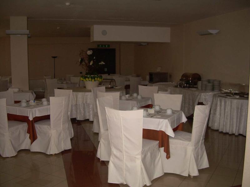 Ein heller Raum mit rund gedeckten Tischen und weiß bezogenen Stühlen, festlich dekoriert.