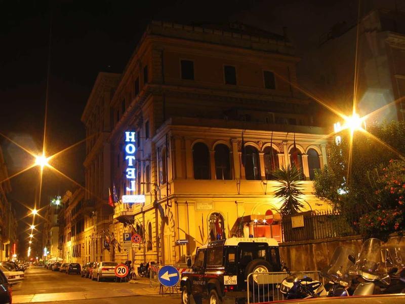 Verlicht hotelgebouw 's nachts met auto's en motorfietsen ervoor