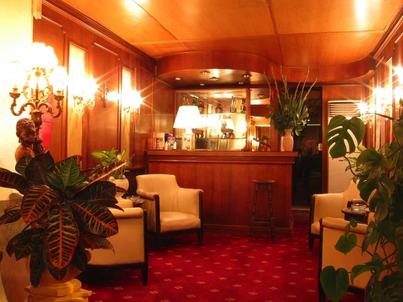 Gezellige hotellobby met rood tapijt, houten betegeling en comfortabele fauteuils.