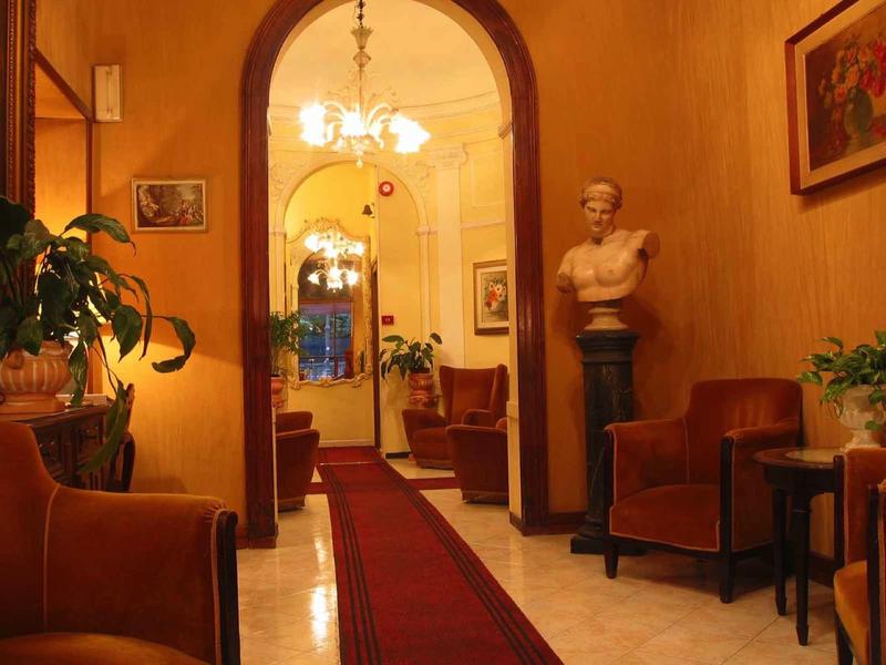 Elegante hotellobby met rode fauteuils, rood tapijt en antieke buste