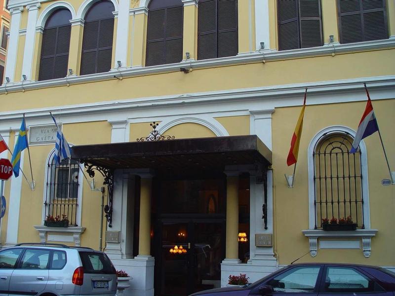 Historisch gebouw met gele gevel en auto's geparkeerd vooraan op straat.