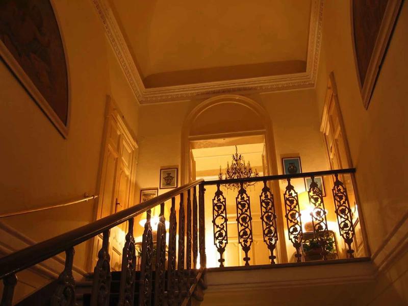 Interieur met trap en decoratief hekwerk in warm verlichte hotelgang.