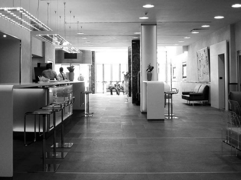 Moderner, offener Raum mit Stühlen und Tischen, großer Fensterfront und gedämpfter Beleuchtung.