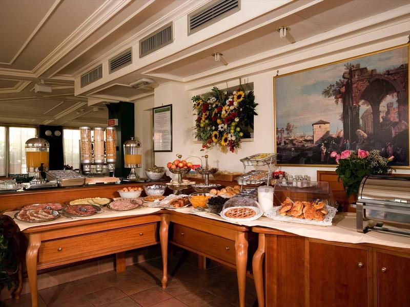 Bufet se snídaňovými pečivy a džusy v elegantní hotelové jídelně.