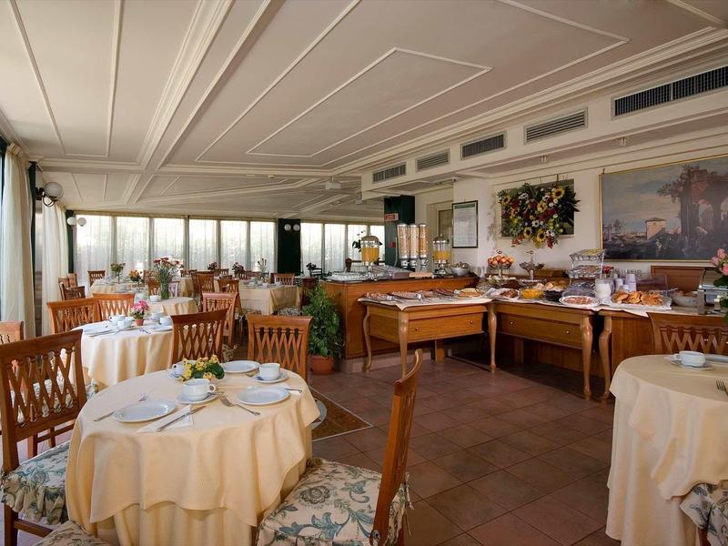 Prosvětlená restaurace s prostřenými stoly a velkými okny s výhledem ven.