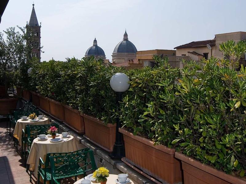 Balkon s prostřenými stoly s výhledem na kupole a kostelní věž za jasné oblohy.