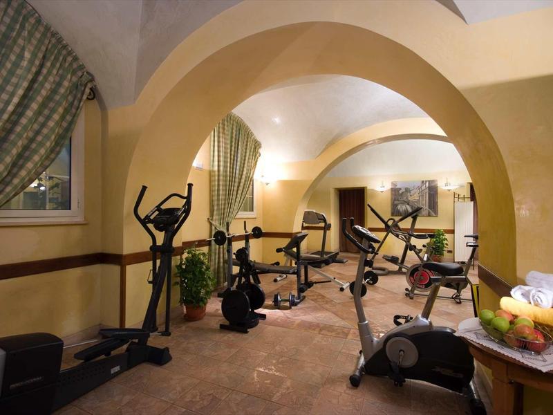 Příjemná posilovna s různými stroji v klenuté místnosti.