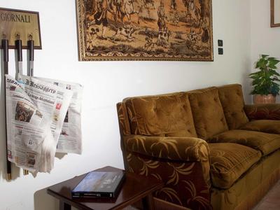 Příjemný posezení s hnědou pohovkou, stojanem na noviny a kobercem na zdi.