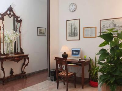 Ingresso elegante con specchio antico, consolle in legno e piccolo spazio di lavoro con computer.