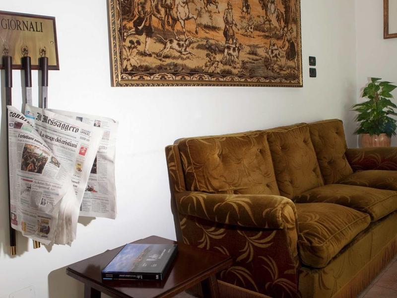 Příjemný posezení s hnědou pohovkou, stojanem na noviny a kobercem na zdi.