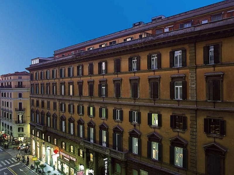 Wielopiętrowy budynek hotelowy wzdłuż ulicy pod czystym niebieskim niebem.