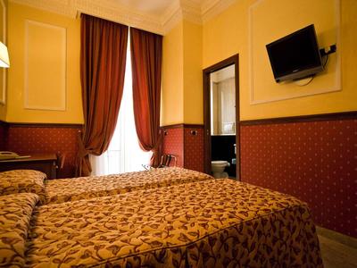 Gemütliches Schlafzimmer mit Doppelbett, roten Vorhängen, Gelb-rot gestrichenen Wänden und Wand-TV.