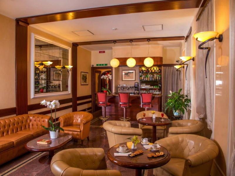 Gemütliche Hotelbar mit Lederstühlen, Holzvertäfelung, runden Tischen und warmem Licht.