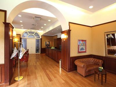 Elegancka lobby hotelowa z drewnianą podłogą, recepcją i przytulnym miejscem do siedzenia pod dużym łukiem.