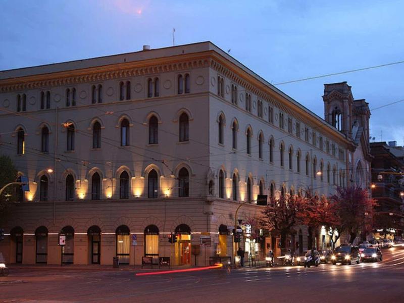 Oświetlony wielopiętrowy budynek na ruchliwym rogu ulicy o zmierzchu.