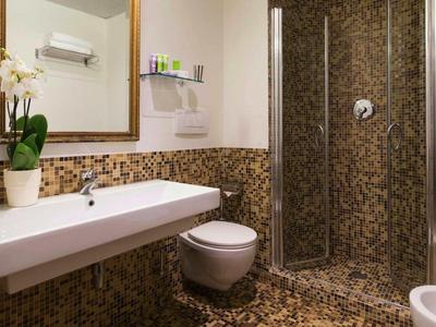 Moderne badkamer met mozaïektegels, wastafel, toilet en douche in een hotelverblijf.