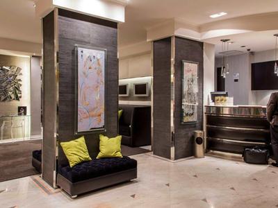 Moderne hotel lobby met receptie en zitgedeelte met gele kussens.