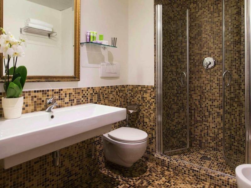Moderne badkamer met mozaïektegels, wastafel, toilet en douche in een hotelverblijf.