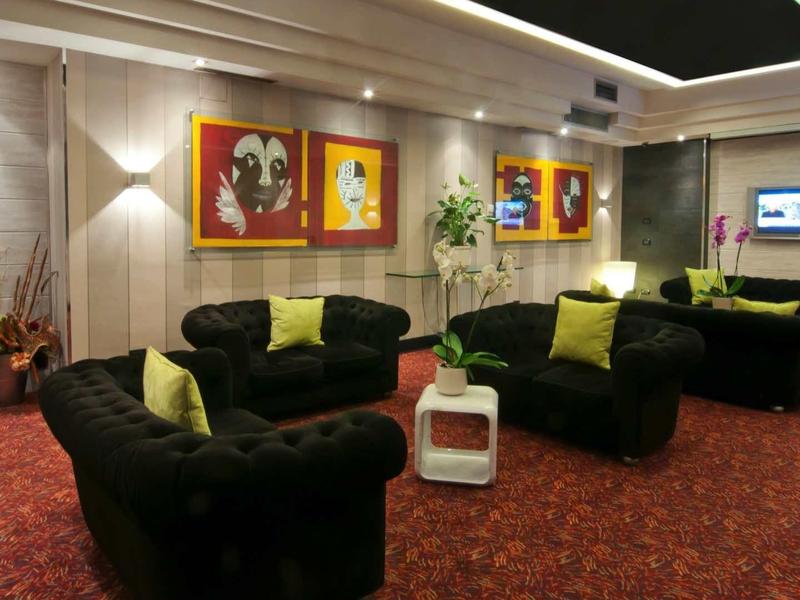 Modern ingerichte hotel lounge met zwarte banken en groene kussens.