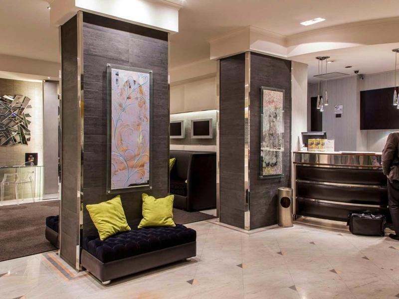 Moderne hotel lobby met receptie en zitgedeelte met gele kussens.