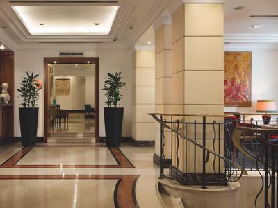 Elegante Hotellobby mit Marmorboden, Pflanzen und Sitzbereich unter warmem Licht.