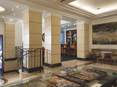 Hall d'hôtel lumineux avec réception et espace de sièges, éclairage moderne et art mural décoratif.